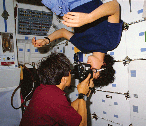 Astronaut Franklin R. Chang-Diaz performs an eye exam on astronaut Ellen S. Baker, MD, MPH, on the middeck of the Earth-orbiting space shuttle Atlantis.
